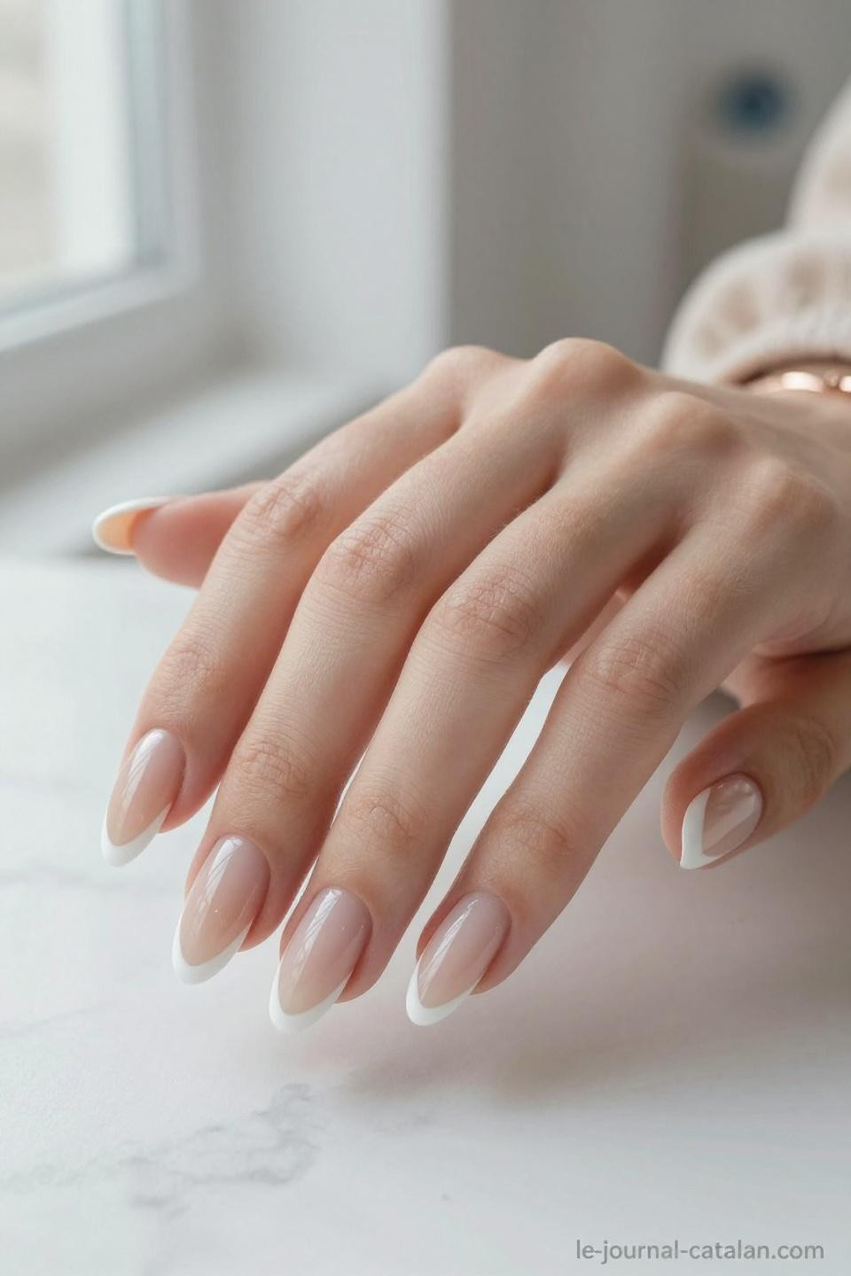 Classic French manicure on almond nails with pristine white tips and nude pink base