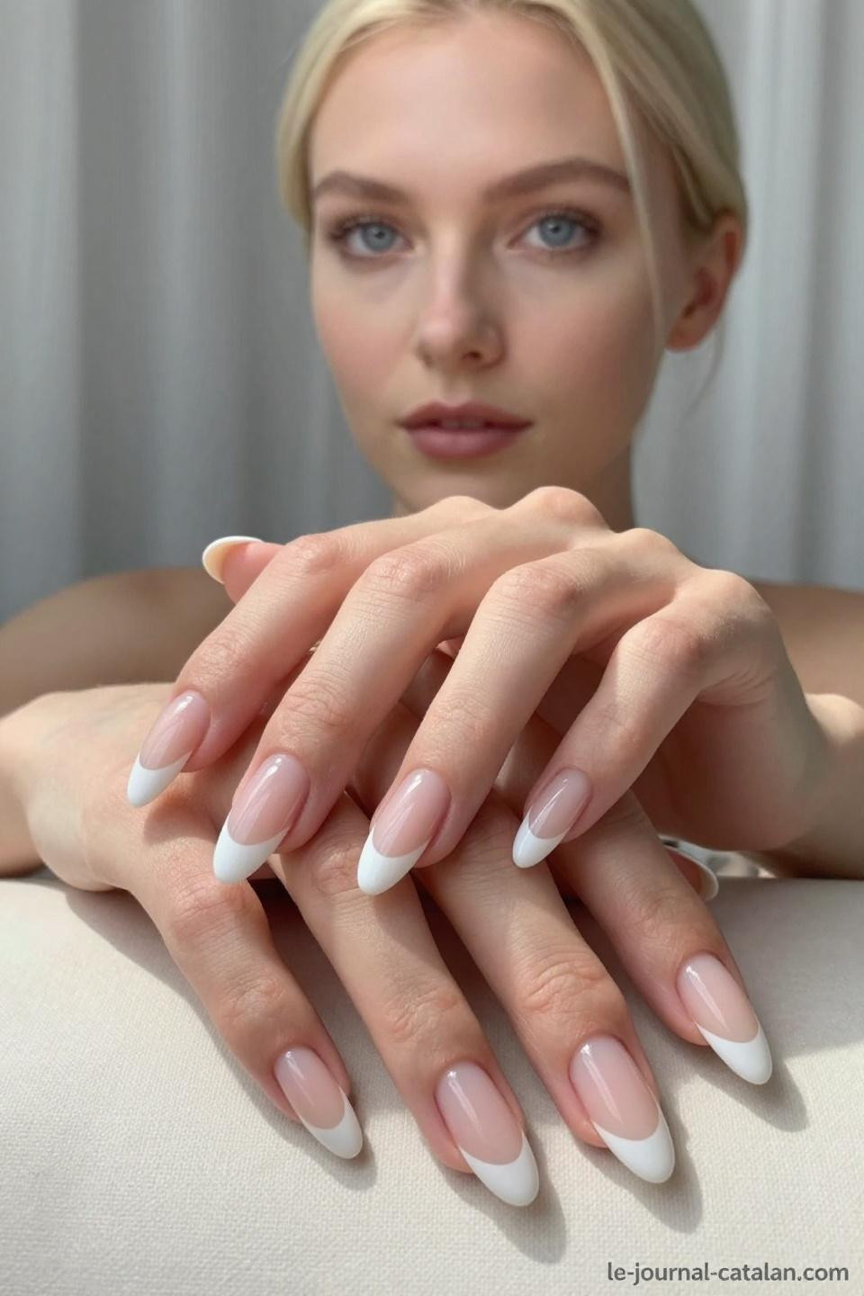 Pristine almond French tips with milky white tips and nude pink base on porcelain hands