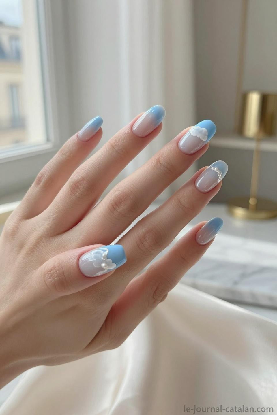 Baby blue nails with delicate white cloud nail art on almond shaped nails