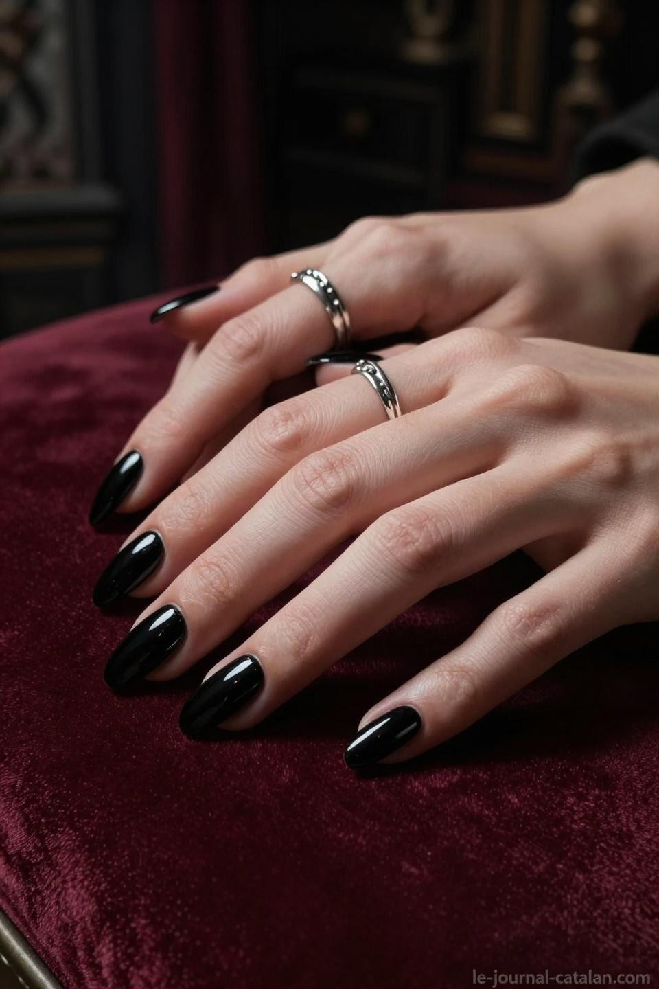 dark feminine nails in glossy black almond shape against burgundy velvet with gothic lighting