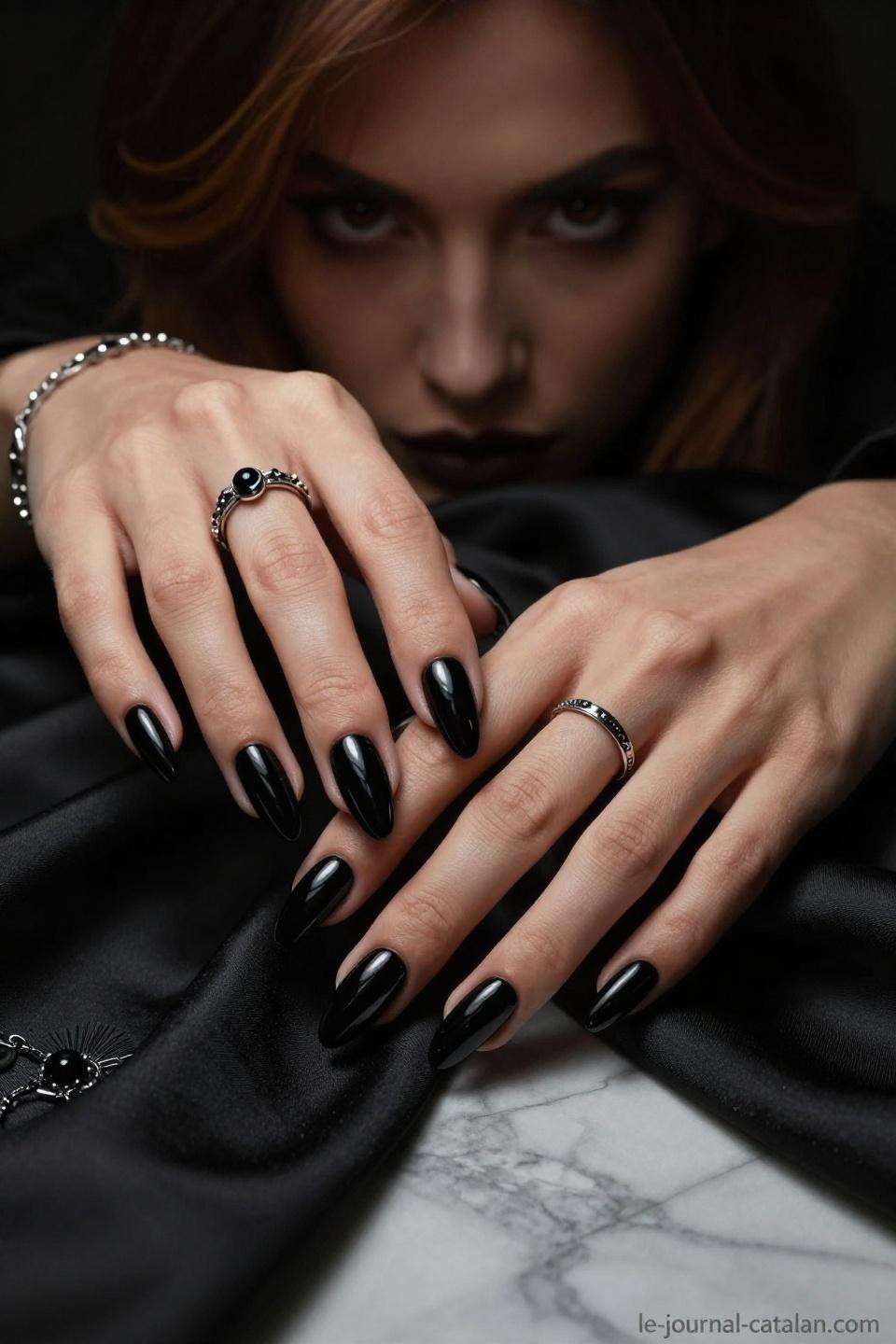 black almond nails with gothic jewelry and oxidized silver rings on marble surface