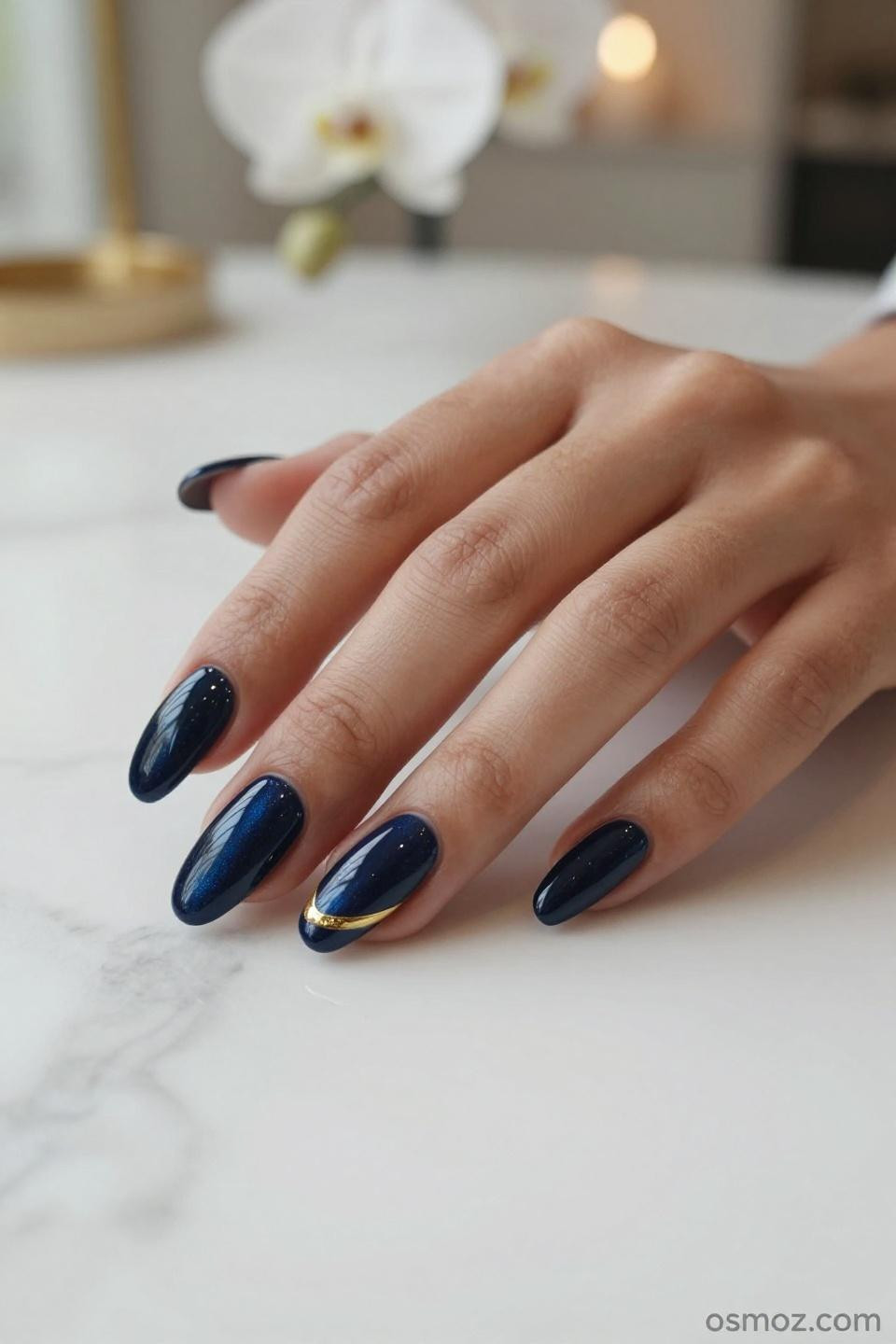 Blue Nails Ideas with glossy navy gel and gold metallic stripe on almond nails
