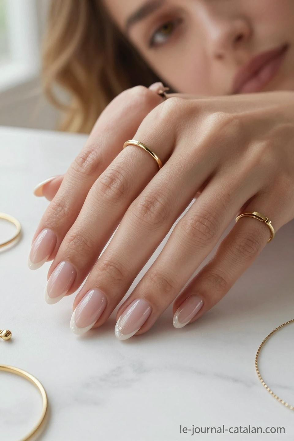 Short almond nails with nude pink base and delicate gold ring accents